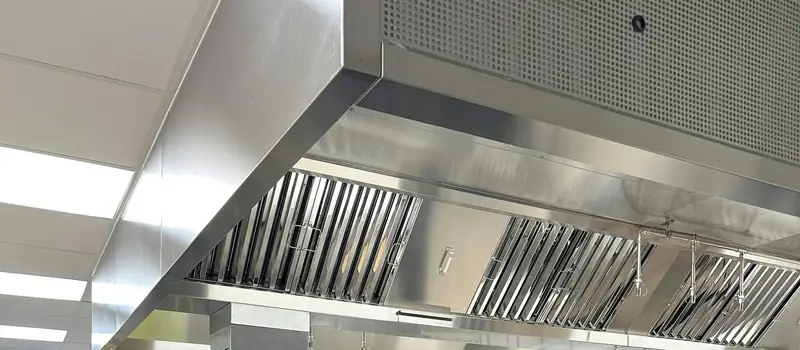 Close view of a commercial kitchen exhaust hood and its row of baffle grease filters